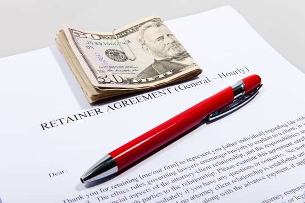 Cash and a red pen resting on an attorney retainer agreement.