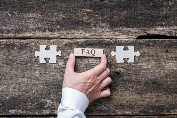 Hands joining puzzle pieces around an FAQ tile.