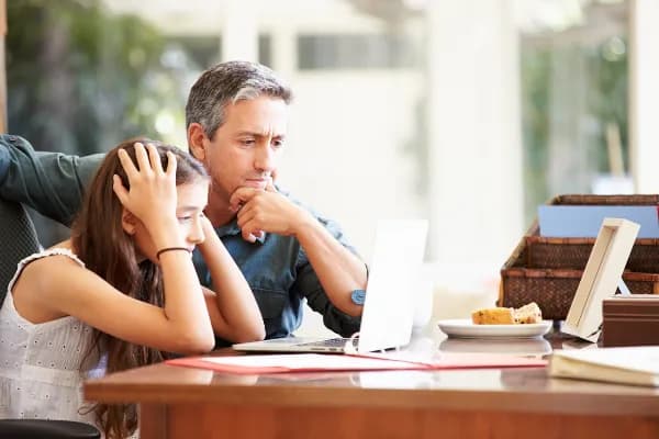 Man and woman sitting at a table with a laptop and papers.