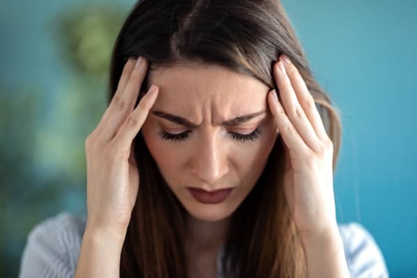 Woman holding her temples with a worried expression.